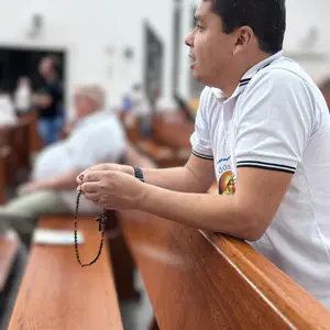 Homens em oração no encontro semanal do Terço